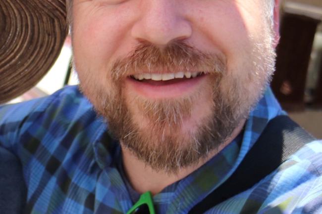 Will Smiles with a beard, wearing a blue plaid shirt