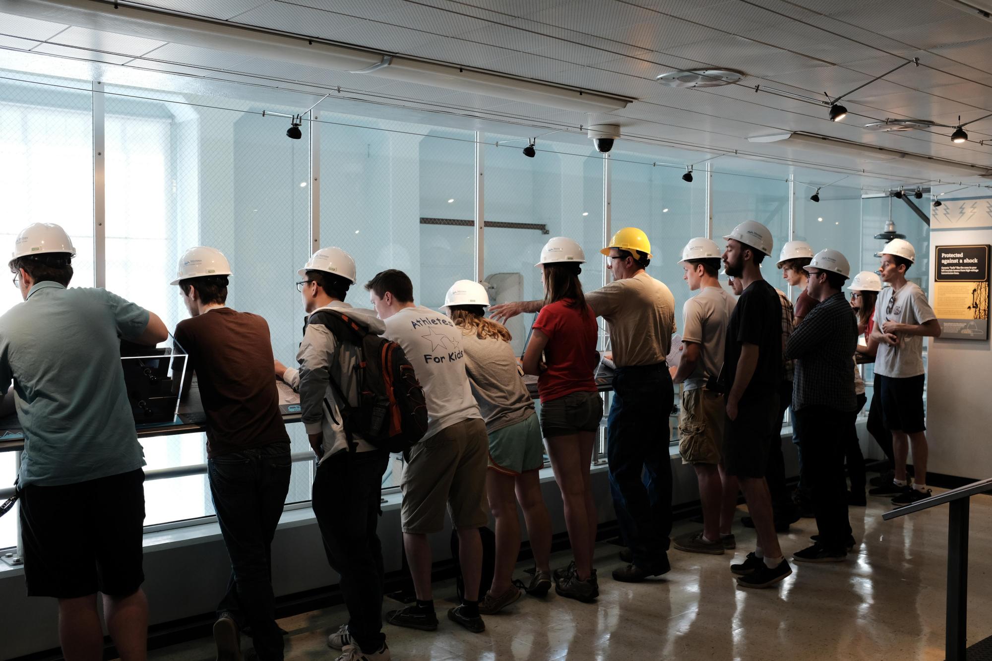 Students wear hard hats and look over a balcony