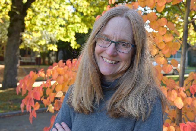 Eileen smiling arms crossed, backed by stunning autumn foliage