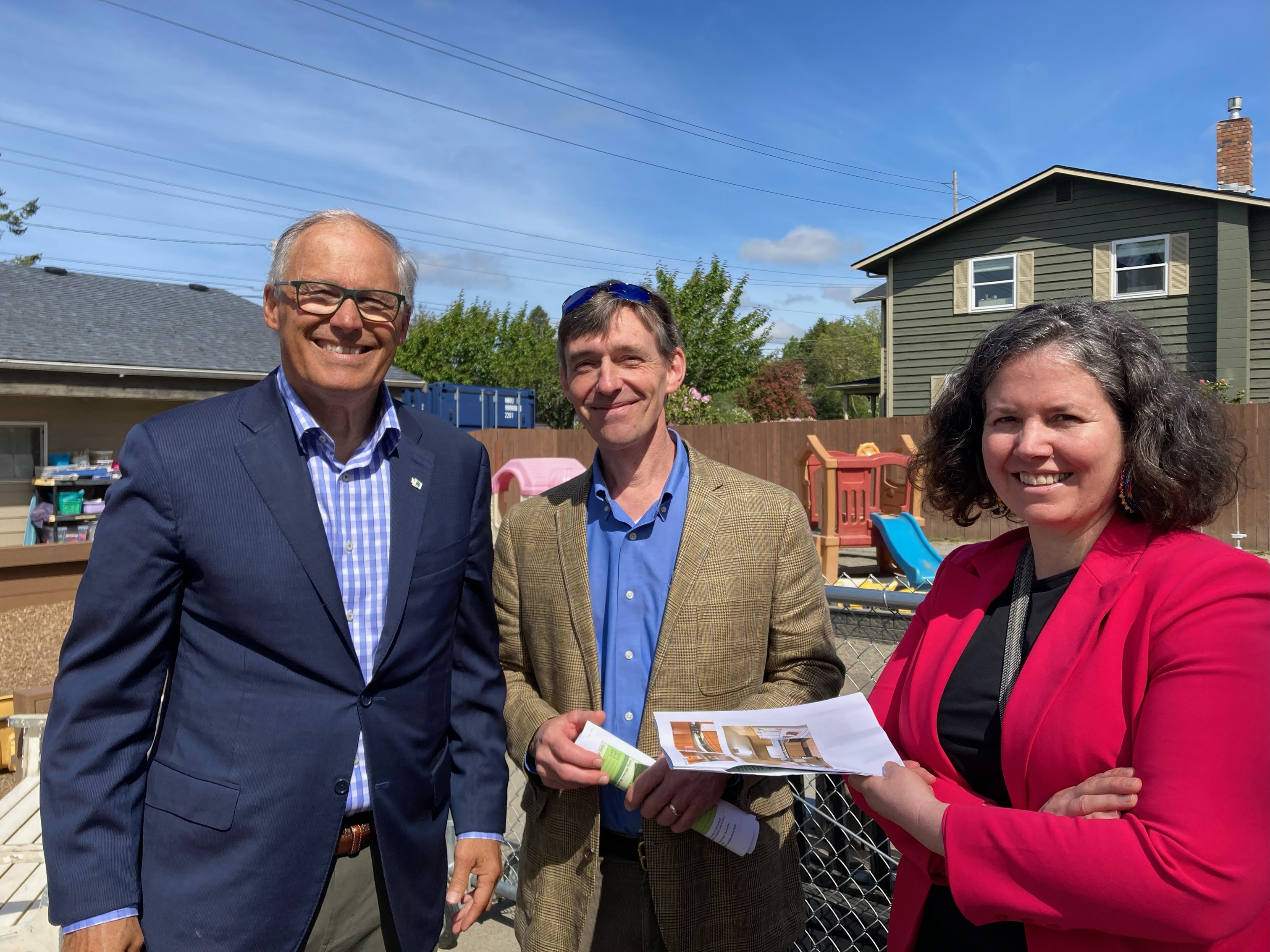 From left to right: Governor Jay Inslee, IES Director Darrin Magee, and IES faculty and Washington Senator Sharon Shwemake. The group is standing in a small playground and there are low buildings in the background.