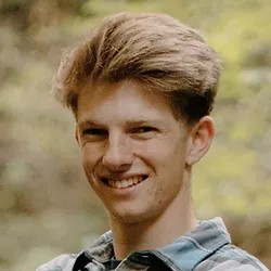 Anders Johnson is a fair skinned male with light brown hair. He is smiling at the camera and is wearing a collared button down shirt.